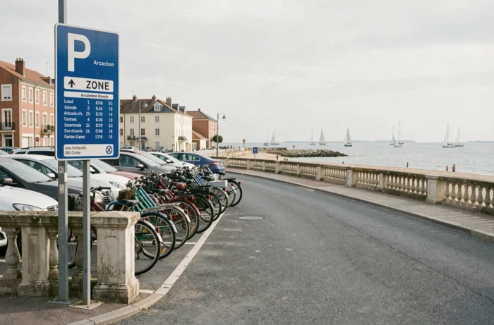 Zone de stationnement en bord de mer à Arcachon avec panneau d'information et vue sur le bassin